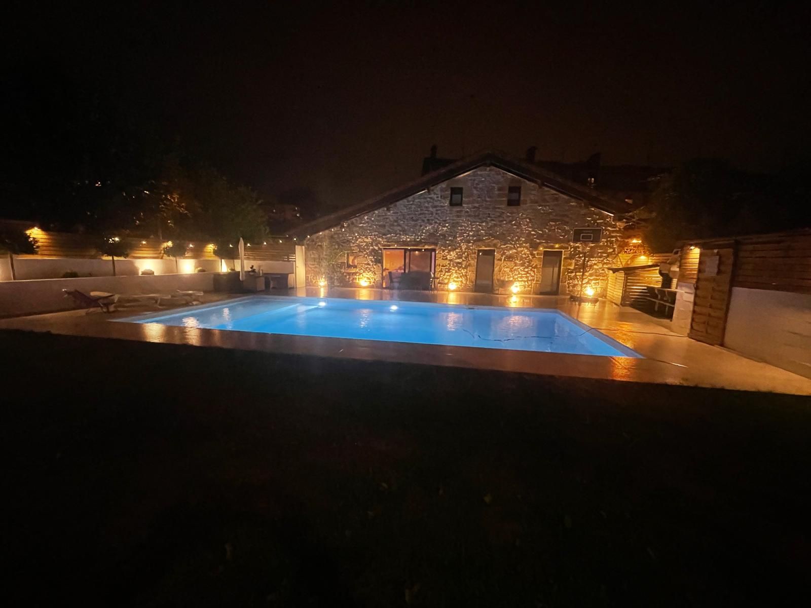 Casa de piedra rehabilitada con piscina iluminada por la noche